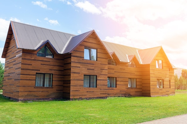 Cabaña de madera de dos plantas con ventanas naturaleza con césped verde. Venta o compra de casas nuevas.