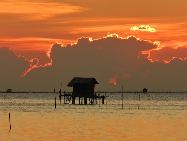 Cabaña de pescadores de silueta durante la puesta de sol