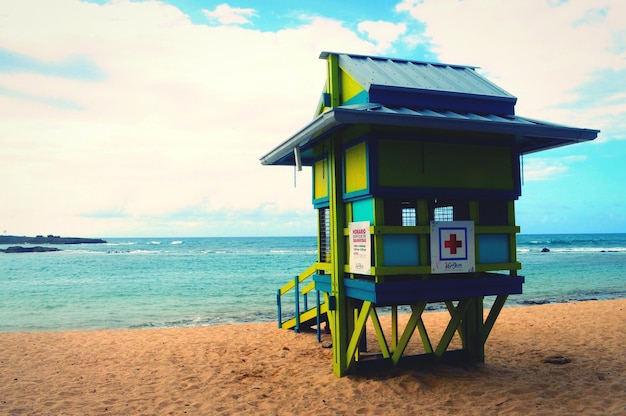 Foto cabaña de socorristas con signo más en la playa contra el cielo