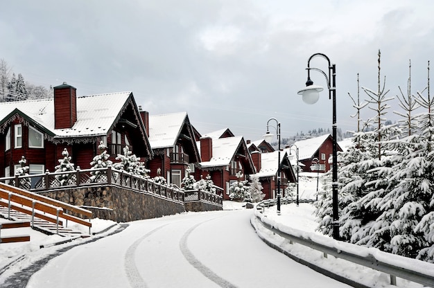 Cabañas de madera, casa de vacaciones en la montaña, cubierto de nieve fresca en invierno. Hermosa calle de invierno después de las nevadas.