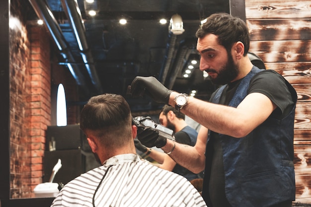 Cabeça de corte de cabelo na barbearia. O barbeiro corta o cabelo na cabeça do cliente. O processo de criação de penteados para homens. Barbearia. Foco seletivo.