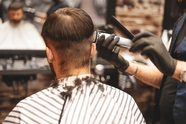 Foto cabeça de corte de cabelo na barbearia. o barbeiro corta o cabelo na cabeça do cliente. o processo de criação de penteados para homens. barbearia. foco seletivo.