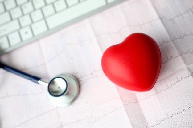 Foto cabeça de estetoscópio médico e coração de brinquedo vermelho