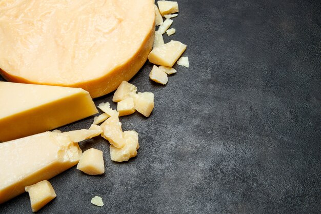 Cabeça de queijo parmesão e pedaços na mesa de concreto