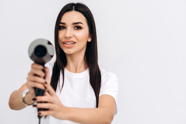 Cabeleireiro alegre, mulher posando com um secador de cabelo nas