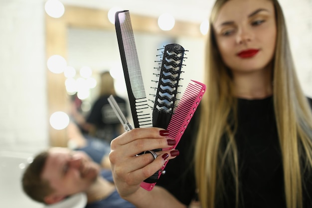 Cabeleireira segurando pente e tesoura na barbearia