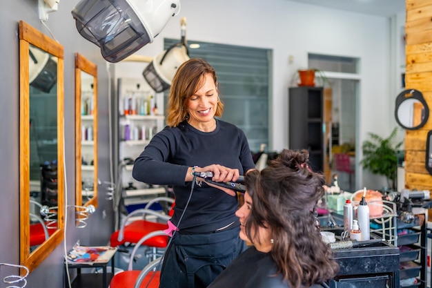 Foto cabeleireiro a passar o cabelo de uma mulher no salão.