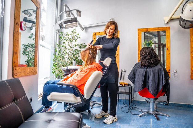 Foto cabeleireiro a pentear o cabelo de um cliente no salão