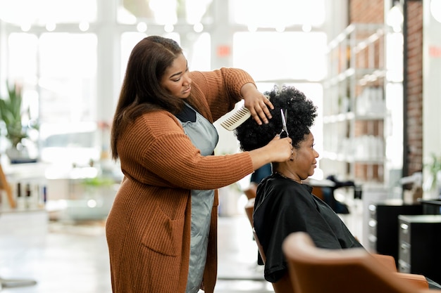 Foto cabeleireiro aparando o cabelo da cliente em um salão de beleza