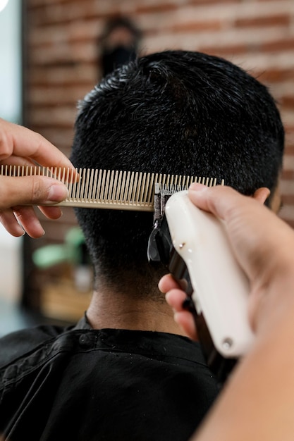 Cabeleireiro aparando o cabelo da cliente em uma barbearia