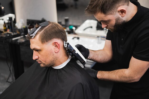 Cabeleireiro brutal cortando o cabelo dos clientes com tosquiadeira