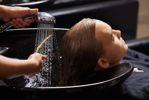 Foto cabeleireiro cabeleireiro lavando o cabelo do cliente jovem relaxando no salão de beleza de cabeleireiro