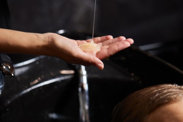 Foto cabeleireiro cabeleireiro lavando o cabelo do cliente jovem relaxando no salão de beleza de cabeleireiro