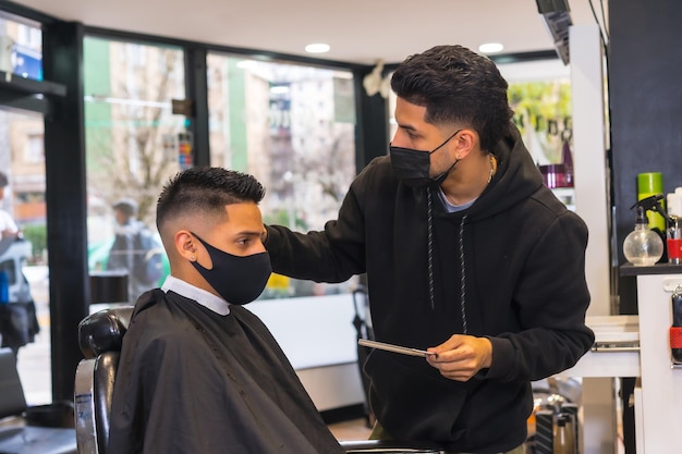 Cabeleireiro com máscara facial terminando o corte para o cliente