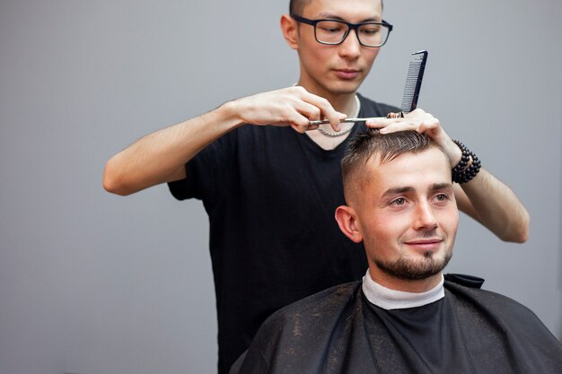 Cabeleireiro corta o cabelo de um cliente em uma barbearia