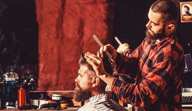 Cabeleireiro cortando o cabelo de um cliente do sexo masculino. cabeleireiro atendendo cliente na barbearia. homem visitando cabeleireiro na barbearia.