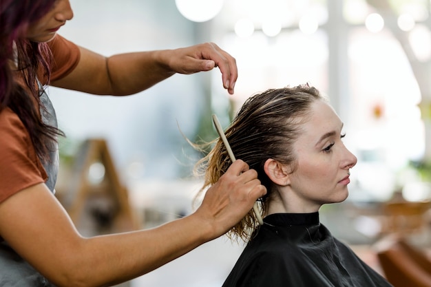 Cabeleireiro cortando o cabelo de uma cliente em um salão de beleza