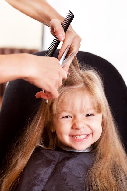 Cabeleireiro cortando o cabelo de uma menina loira