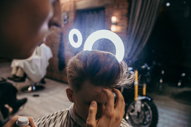 Cabeleireiro de cortes de cabelo de menino ruivo adolescente na barbearia. Penteado retrô elegante e elegante. Retrato de uma criança com um corte de cabelo bonito.