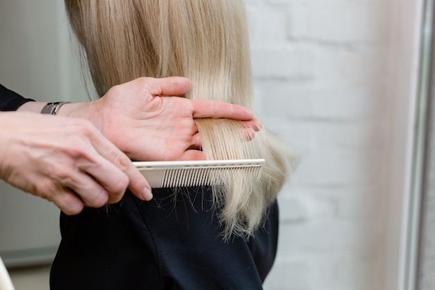 Cabeleireiro fazendo corte de cabelo. Tesoura de cabeleireiro profissional, escova no local de trabalho. Ferramentas de cabeleireiro profissional, equipamentos. Serviço de cabeleireiro. Serviço de salão de beleza. Feche com espaço para texto.