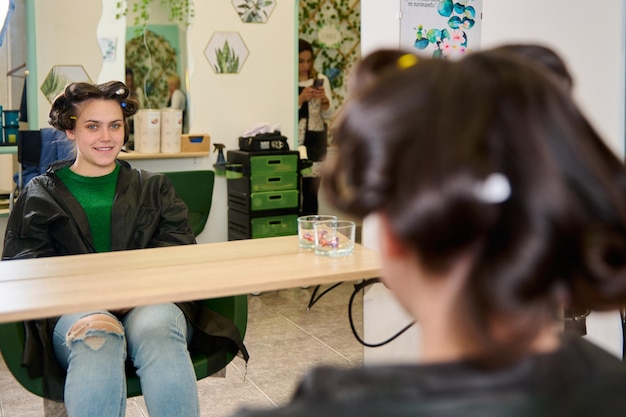 cabeleireiro fazendo maquiagem e estilizando uma jovem cliente do sexo feminino em um salão de beleza