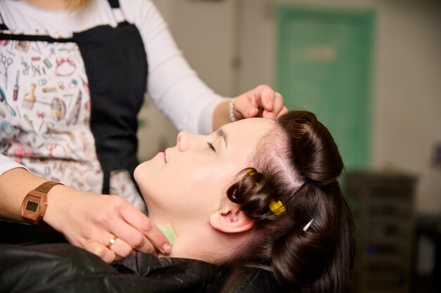 cabeleireiro fazendo maquiagem e estilizando uma jovem cliente do sexo feminino em um salão de beleza