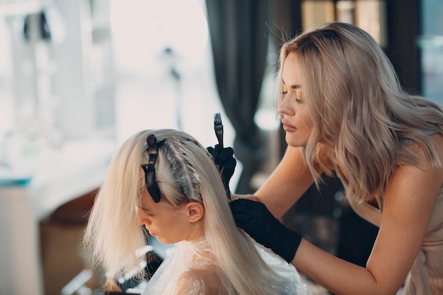 Cabeleireiro jovem morrendo de cabelo no salão de beleza Coloração profissional de raízes de cabelo