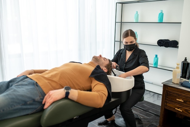 Cabeleireiro lavando o cabelo para seu cliente masculino