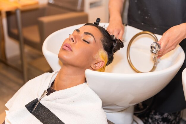 Foto cabeleireiro, limpando o cabelo com água quente e sabão para um cliente