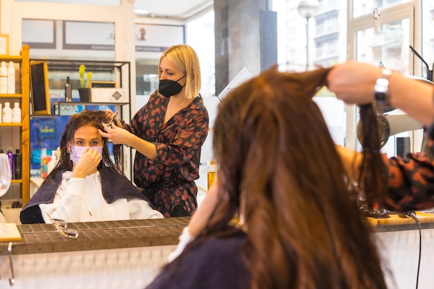 Cabeleireiro loiro com máscara de proteção facial realizando um penteado ao cliente Medidas de segurança na pandemia Covid19