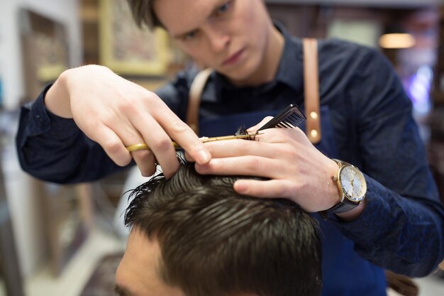 Foto cabeleireiro masculino a cortar o cabelo na barbearia