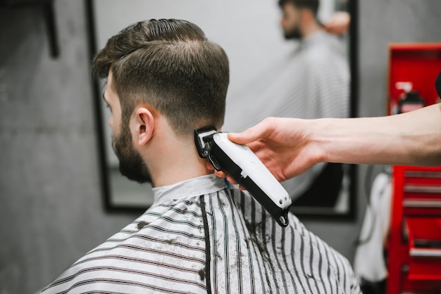 Cabeleireiro masculino profissional faz penteado para homem barbudo na barbearia