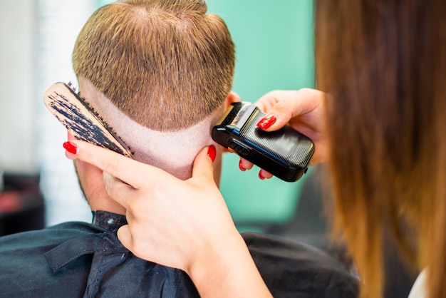 Cabeleireiro menina seca o cabelo para um homem em um salão de beleza