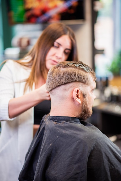 Cabeleireiro menina seca o cabelo para um homem em um salão de beleza