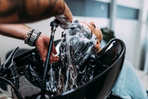 Cabeleireiro profissional lavando o cabelo de clientes. fechar-se.