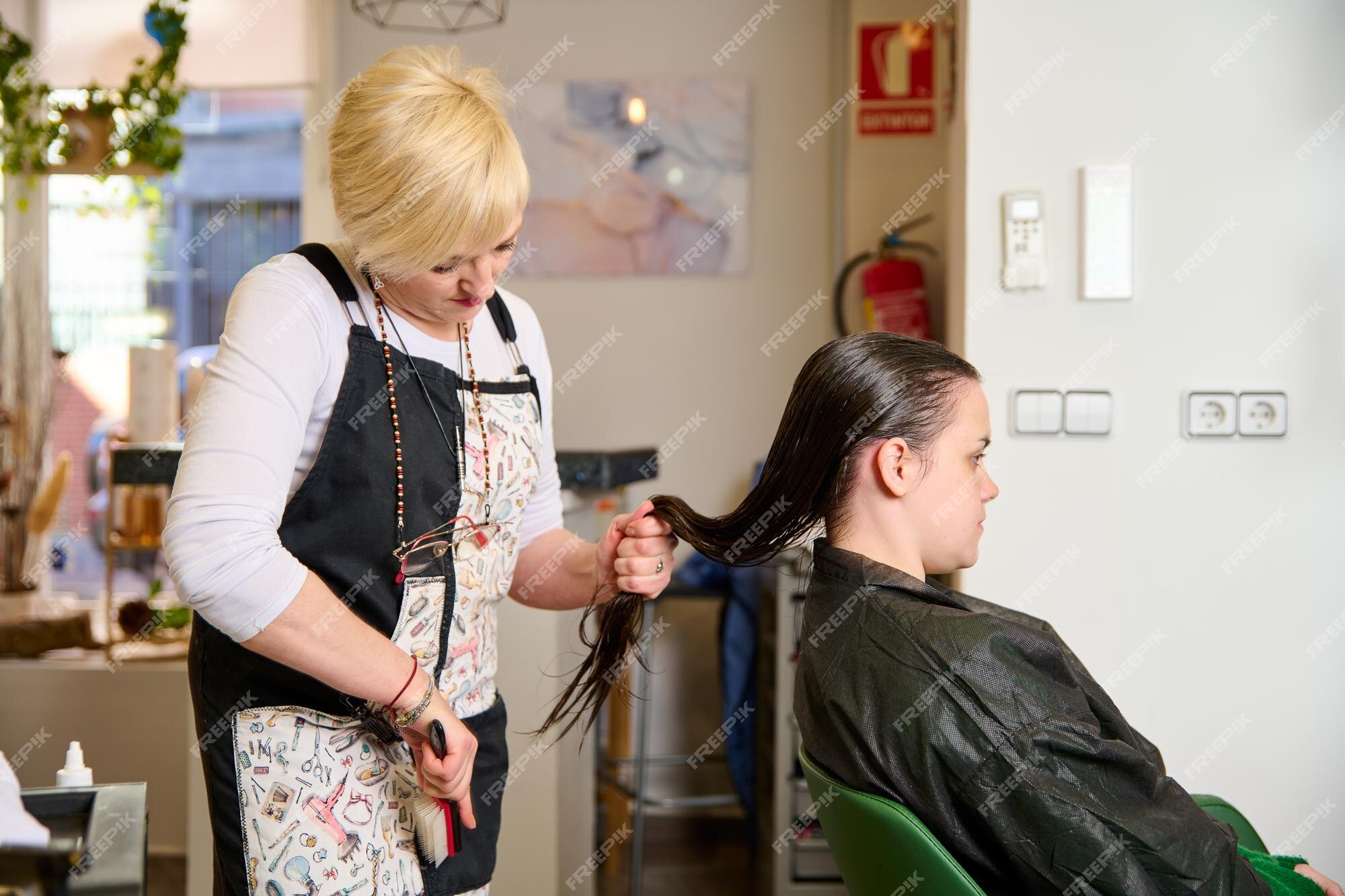 Cabeleireiro seca e modela o cabelo com um secador de cabelo no salão de  beleza