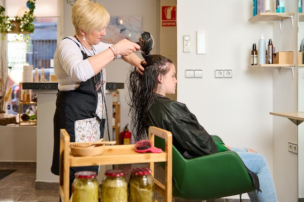 Cabeleireiro seca e modela o cabelo com um secador de cabelo no salão de beleza