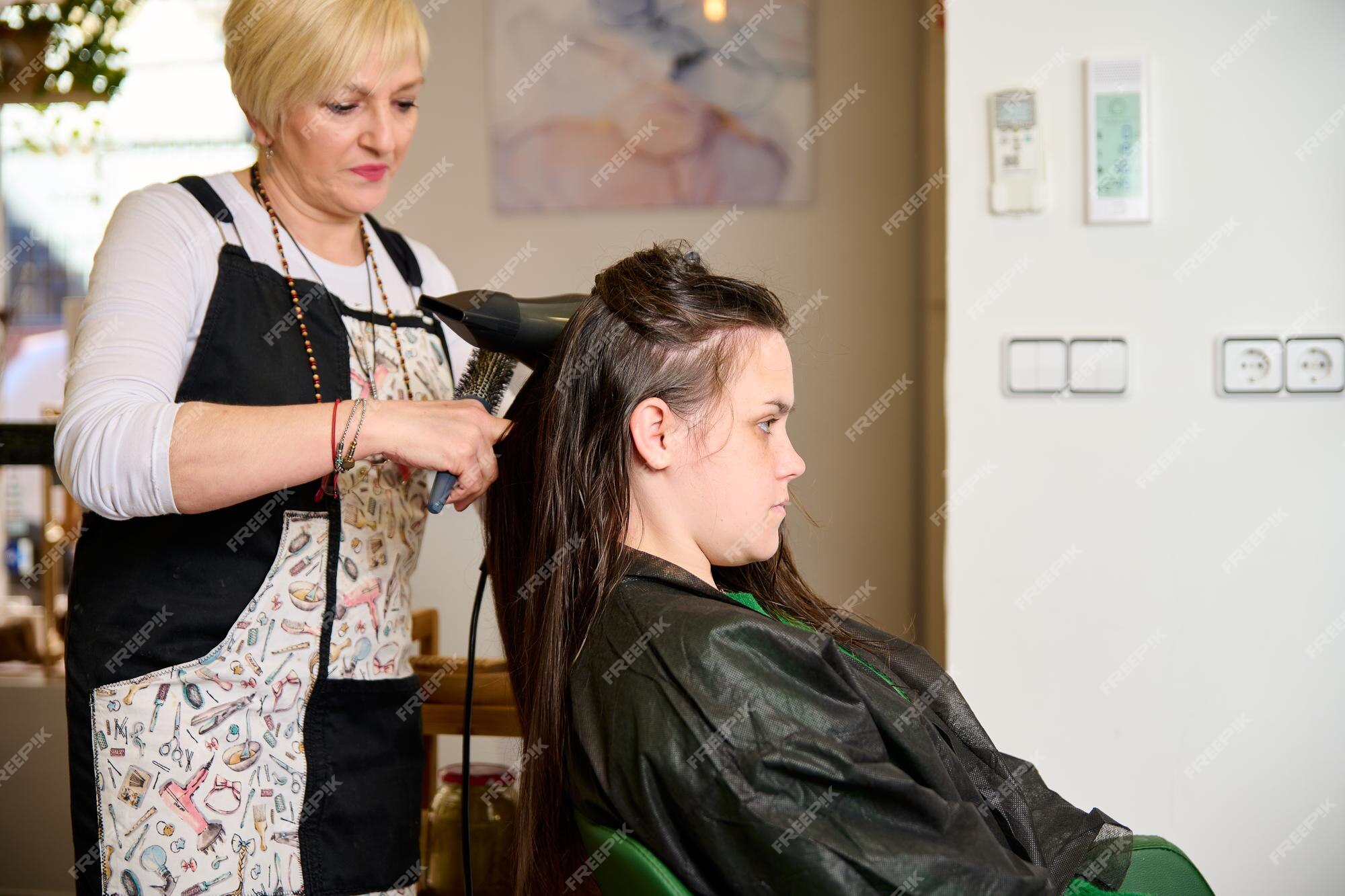 Cabeleireiro seca e modela o cabelo com um secador de cabelo no