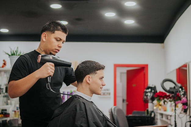 Cabeleireiro secando o cabelo de seu cliente com pente e secador com espaço para cópia