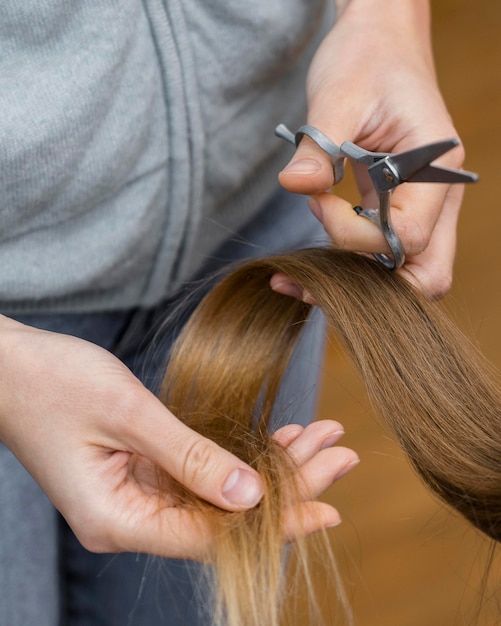 Foto cabeleireiro segurando uma mecha de cabelo e uma tesoura