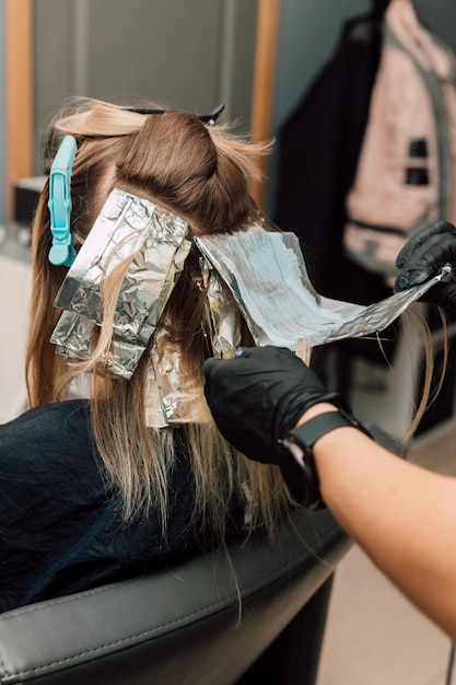 Cabeleireiro selando um fio de cabelo tingido em papel alumínio