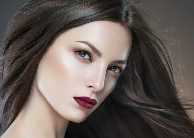 Cabello belleza mujer larga bruette suave hermosa manicura uñas modelo lápiz labial rojo fondo marrón retrato de maquillaje de noche. Tiro del estudio.