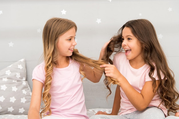 Cabello fuerte Los niños juegan alegremente con el cabello en el dormitorio Momentos felices de la infancia Niños niñas hermanas mejores amigas llenas de energía en un estado de ánimo alegre Crecer un cabello fuerte y saludable Concepto de cuidado del cabello