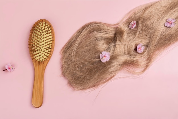 Foto cabello largo rubio con flores de sakura en fondo rosa