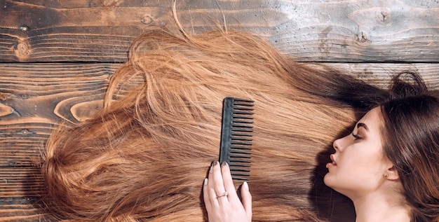 Cabello perfecto. Cabello largo morena rubia. Fondo de madera de mujer perfecta. Belleza y salud perfecta