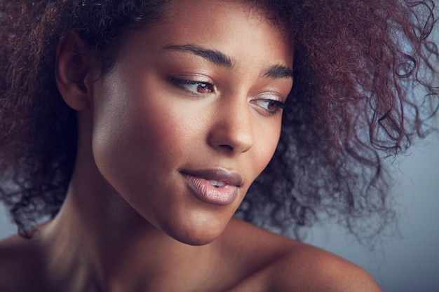 Cabello rizado de mujer africana y pensamiento en estudio con cosméticos de maquillaje y visión por fondo Modelo de niña y bienestar con estética natural para el cuidado de la piel y brillo en la cara con belleza por telón de fondo