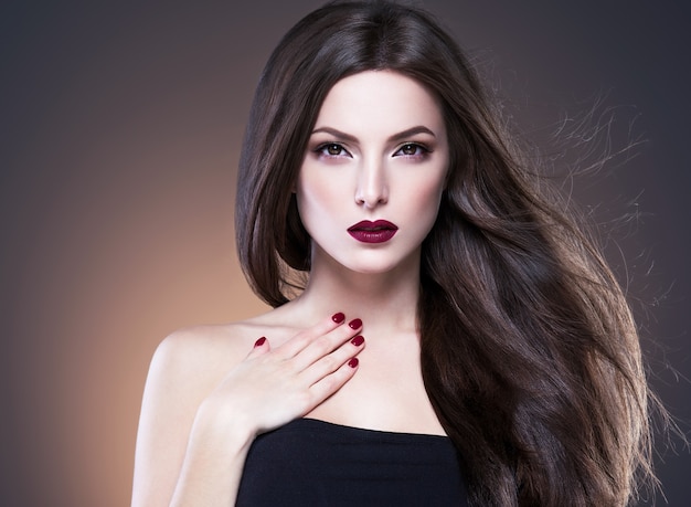 Cabelo beleza mulher longa bruette lisa linda manicure unhas modelo batom vermelho fundo marrom retrato de maquiagem de noite. Tiro do estúdio.