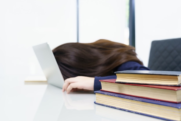 Cabelo comprido de mulher jovem adormecer na mesa com o laptop