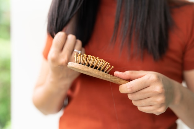 Cabelo comprido em escova de mulher com mulher olhando para o cabelo