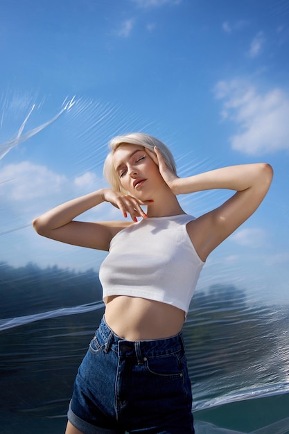 Cabelo curto de mulher loira perfeita. Moda mulher posa no verão na natureza em um dia ensolarado. Manicure de unha vermelha